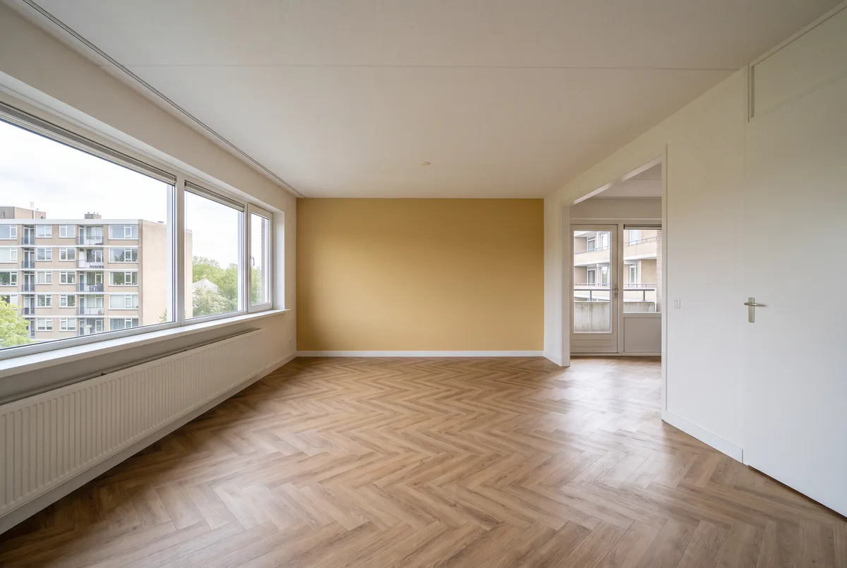 Lege woonkamer van een flat jaren 70: strookraam over de hele gevel, balkon