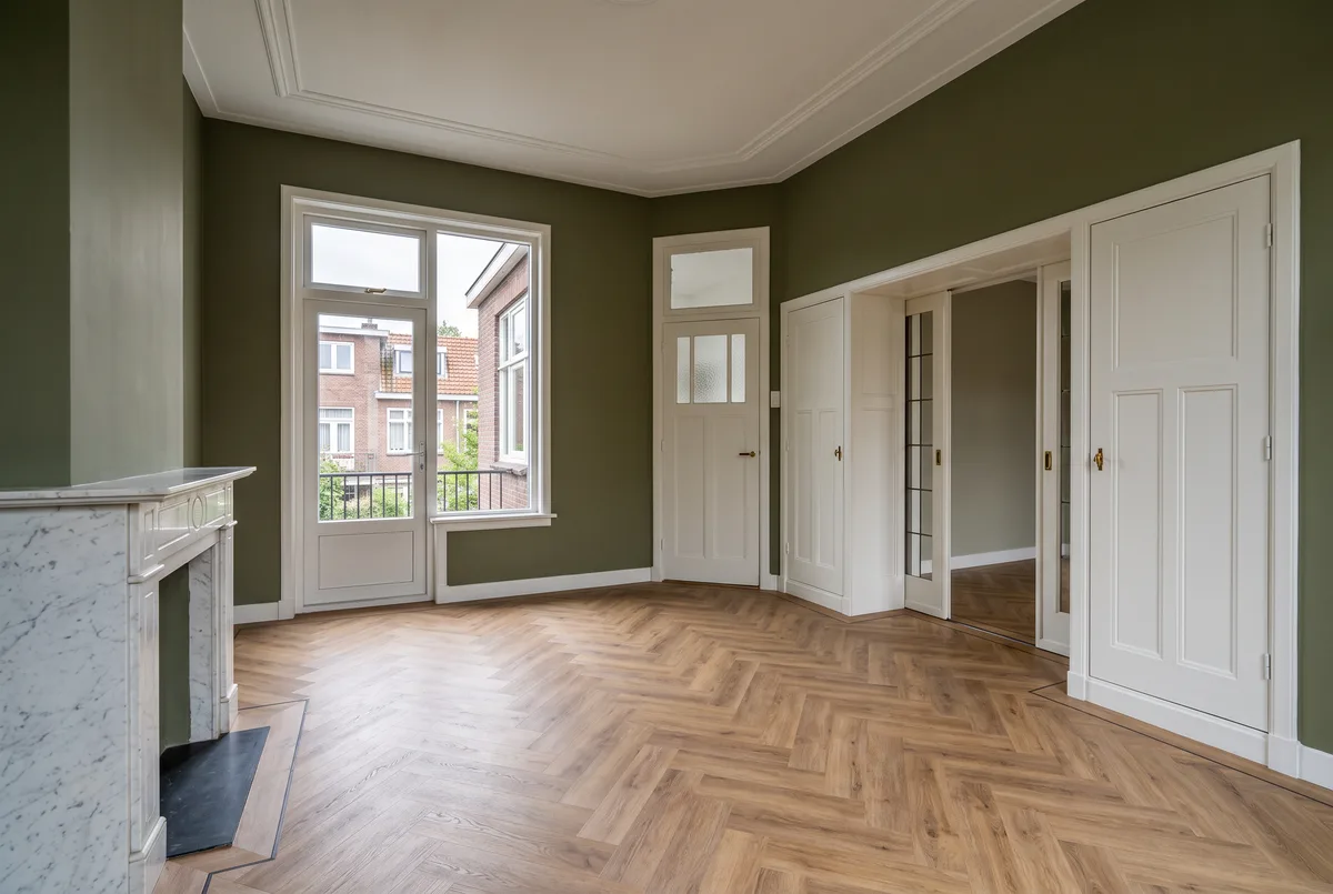 Lege woonkamer van een jaren-30-bovenwoning: schouw, kast-en-suite, hoge plafonds